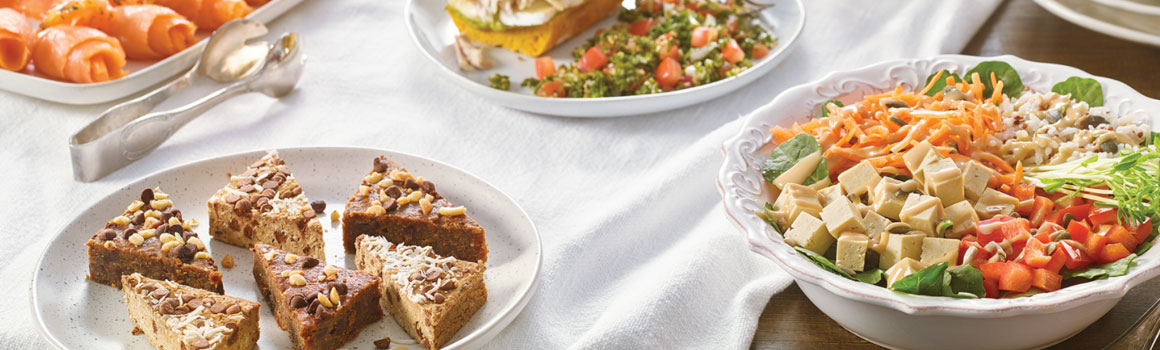 Grande table avec produits frais: sandwichs, salades et rouleaux de saumon fumé.